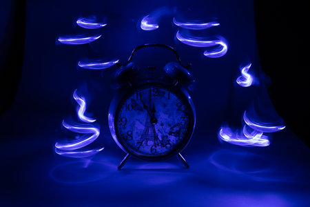 Alarm clock in blue light. Time concept. Close up.の写真素材