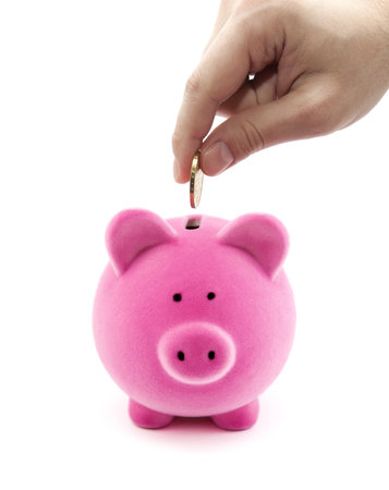 Putting coin into the piggy bankの写真素材