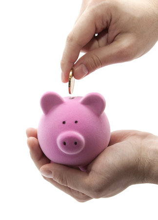 Putting coin into the piggy bank の写真素材