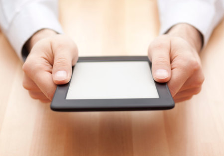 Tablet or e-book reader in hands on wood backgroundの写真素材