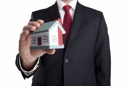 Businessman with house miniature in hand isolated on whiteの写真素材