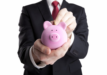 Businessman putting coin into the piggy bankの写真素材