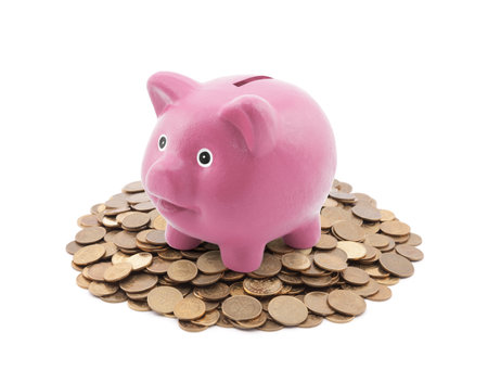 Pink piggy bank on a pile of coinsの写真素材