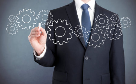 Businessman drawing gears with chalkの写真素材