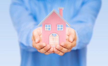 Small pink toy house in handsの写真素材