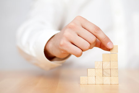 Man putting wooden blocks in the shape of a staircase. Business success concept.
