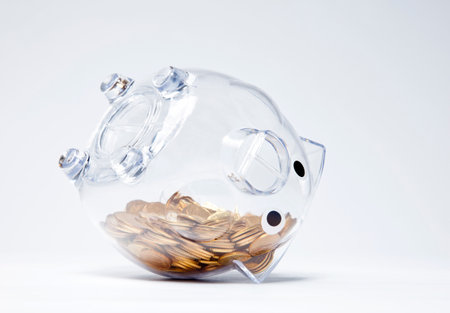 Transparent piggy bank with gold coins upside downの写真素材