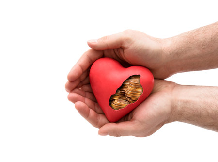 Red heart with golden coins in hands over white background with clipping pathの写真素材