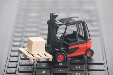 Forklift miniature with wooden block on laptop keyboardの写真素材