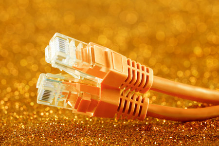 Two network cables over orange sparkles backgroundの写真素材