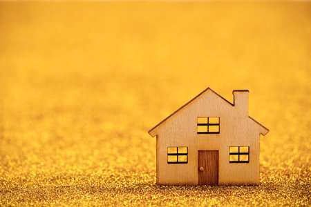 Wooden house shape on golden glitter backgroundの写真素材