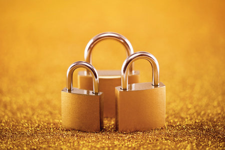 Security concept with three metal padlocks over golden background