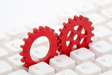 Two red gears on computer keyboardの写真素材