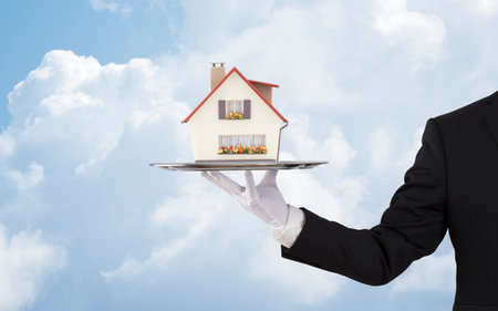 Businessman offering house model on silver trayの写真素材