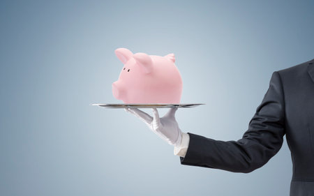 Businessman offering a pink piggy bank on a silver trayの写真素材