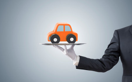 Businessman offering orange car on silver trayの写真素材
