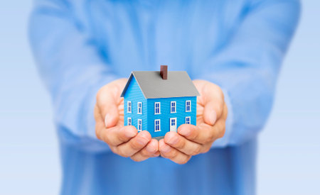 Small blue toy house in handsの写真素材
