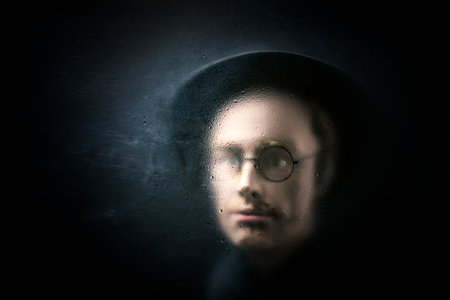Mystery figure with hat and glasses behind a dusty scratched glass.の写真素材