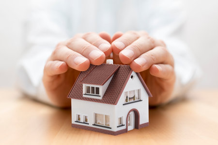 Property insurance. House miniature covered by handsの写真素材