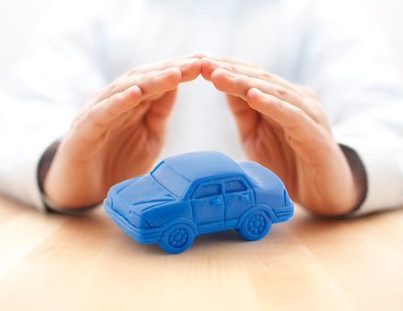 Car insurance concept with blue car toy covered by handsの写真素材