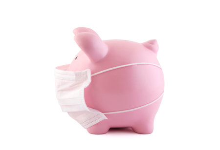 Pink piggy bank with protective medical mask isolated on white with clipping path. Banking during a pandemic conceptの写真素材