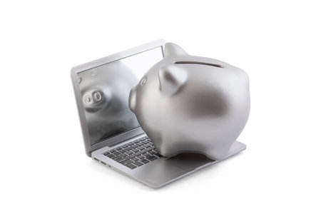 Silver piggy bank on laptop isolated on whiteの写真素材