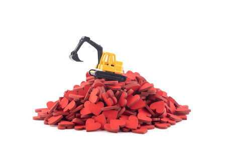 Excavator working on pile of hearts isolated on white background with clipping pathの写真素材
