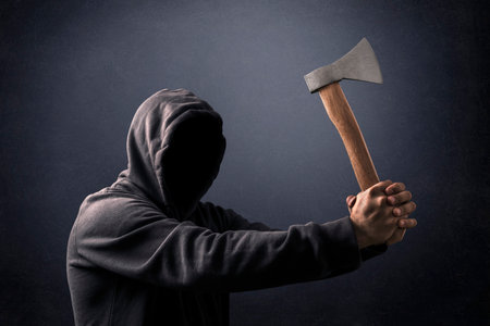 Hooded man with an ax in the dark