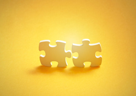 Pair of two matching puzzle pieces on yellow backgroundの写真素材