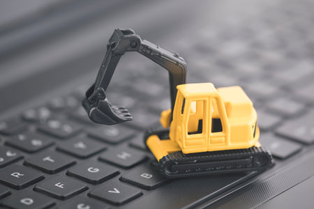 Excavator miniature working on black laptop keybaord
