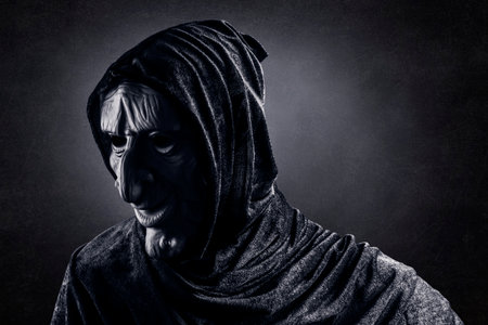 Portrait of a scary witch in hooded cloakの写真素材