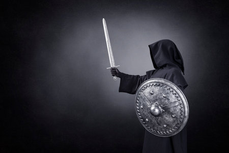 Ghostly figure with sword and round shield in the darkの写真素材