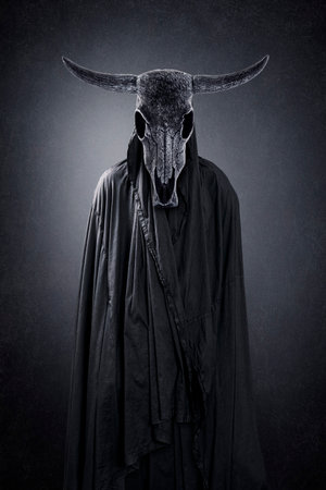 Creepy figure with animal skull with horns in the dark