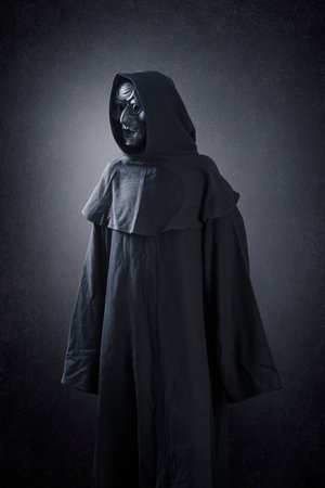 Spooky figure with hooded cape over dark misty backgroundの写真素材