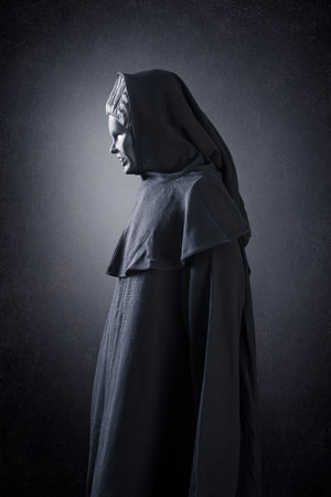Woman ghost in hooded cloak over dark misty backgroundの写真素材