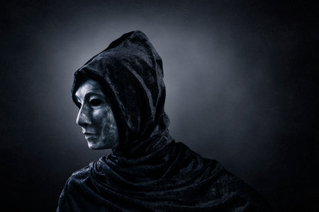 Scary figure with hooded cloak in the darkの写真素材