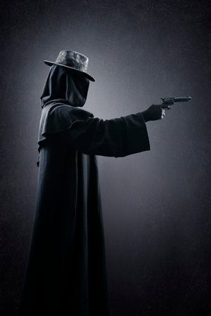 Creepy figure with old hat and gun in the darkの写真素材