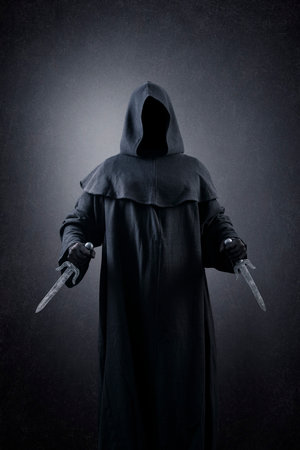 Hooded assassin with two daggers in the darkの写真素材