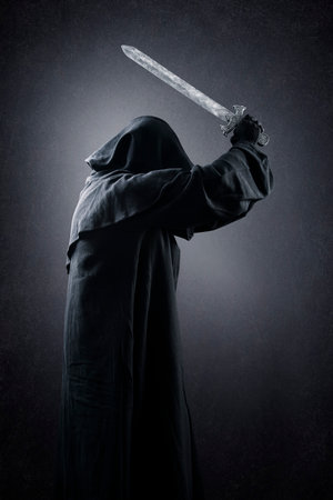 Warrior with hooded cape and medieval sword over dark misty backgroundの写真素材