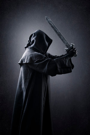 Warrior with hooded cape and medieval sword over dark misty backgroundの写真素材