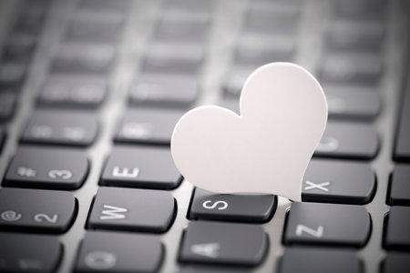 Small white paper heart on computer keyboard. Internet dating concept.の写真素材