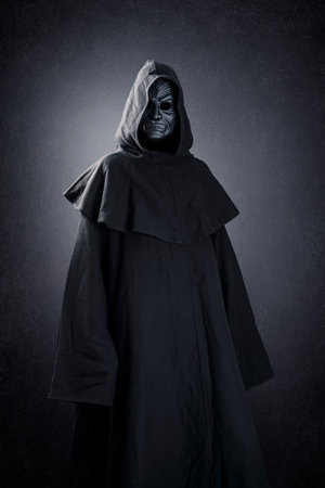 Vampire with cape showing his scary teeth over dark misty backgroundの写真素材