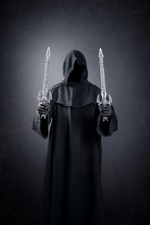 Dark knight with hooded cape and two swords over dark misty backgroundの写真素材