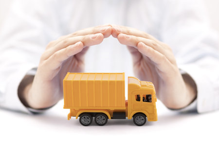 Yellow cargo delivery truck miniature protected by handsの写真素材