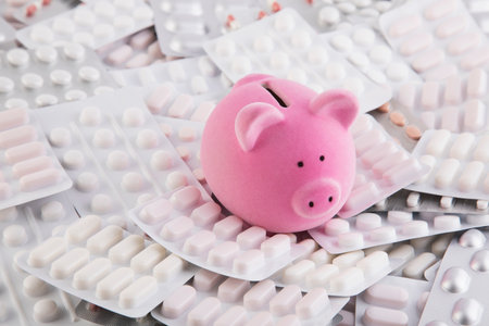 Pink piggy bank on big heap of many various pills and tablets packs for savings and healthcare conceptの写真素材