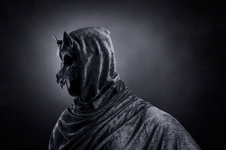Creepy figure with animal skull at night over dark misty backgroundの写真素材