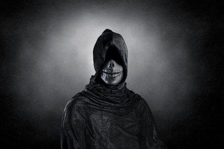 Scary figure with hooded cloak over dark misty background with clipping pathの写真素材