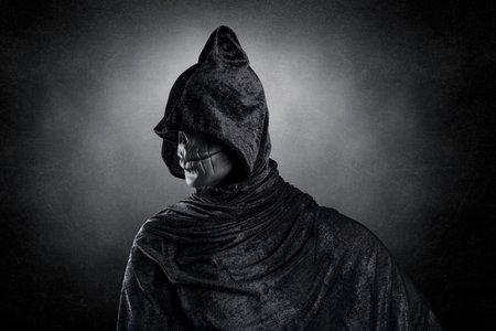 Scary figure with hooded cloak over dark misty background with clipping path