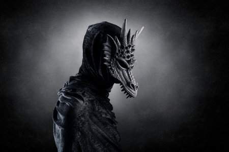Black dragon with hooded cloak over dark misty background with clipping pathの写真素材