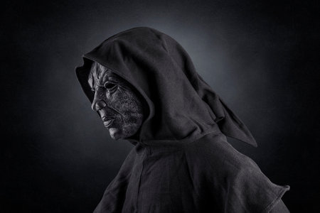 Scary figure with hooded cloak over dark misty background with clipping pathの写真素材